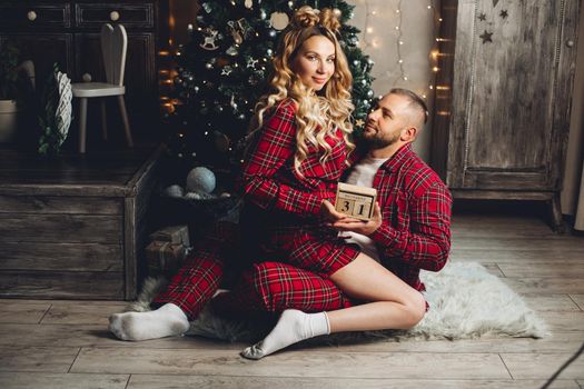 Happy couple of lovers getting ready to celebrate New Year together while sitting on floor at home