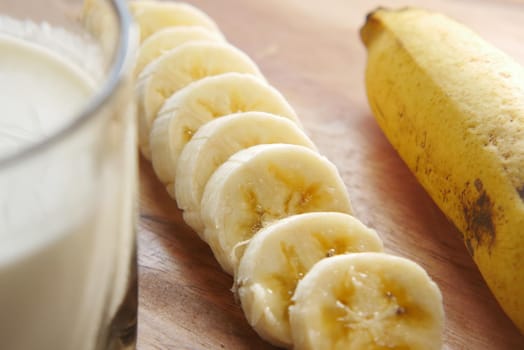 close up of slice of banana glass of milk on table .