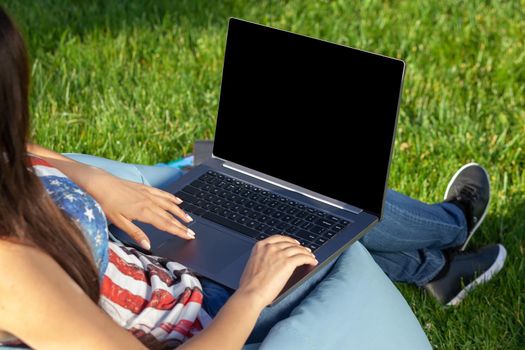 Close up hands on keyboard. Woman working on laptop pc computer with blank black empty screen to copy space in park on green grass sunshine lawn outdoors. Mobile Office. Freelance business concept