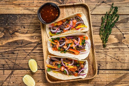 Tacos with beef meat, onion, tomato, sweet pepper and salsa. Mexican food. wooden background. Top view.