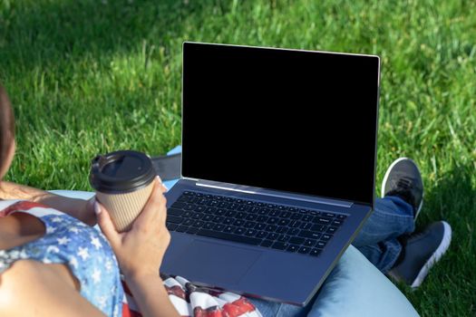 Close up hands on keyboard. Woman working on laptop pc computer with blank black empty screen to copy space in park on green grass sunshine lawn outdoors. Mobile Office. Freelance business concept