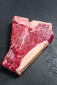 Thick Raw T-Bone Steak. Black background. Top view.