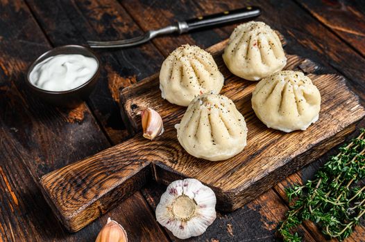 Traditional manti dumplings steamed with mince meat. Dark Wooden background. Top view.