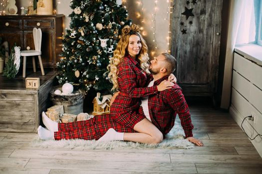 Caucasian woman and man relaxes on the floor in the living room together in christmas atmosphere