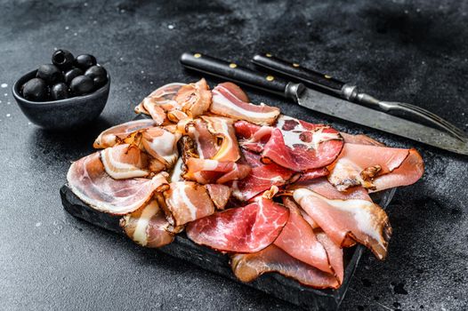 Set of cold cured italian meat Ham, prosciutto, pancetta, bacon. Black background. Top view.