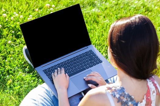 Close up hands on keyboard. Woman working on laptop pc computer with blank black empty screen to copy space in park on green grass sunshine lawn outdoors. Mobile Office. Freelance business concept