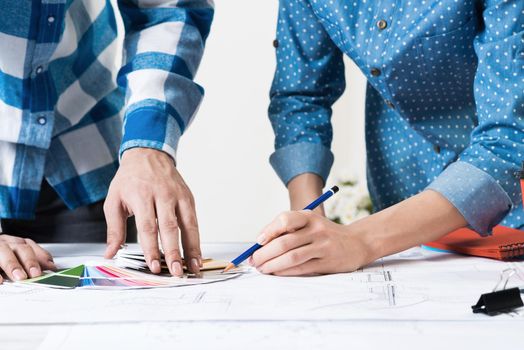 Designers selecting color palette for design project. Human hands, technical drawing and color swatches on desk. Interior design, decoration and renovation. Brainstorming, teamwork and creativity.