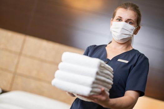 Female housemaid standing with fresh clean towels while cleaning the hotel room. Hotel service concept. Copy space