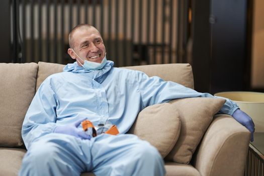 Positive cleaning service worker resting after cleaning in a hotel room. Coronavirus and quarantine concept