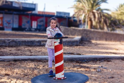 cute little girl holding a ship steering wheel in an amusement park