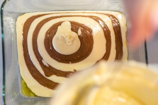 Raw dough for a sweet zebra pie in a baking dish and ingredients for it. Cooking process.