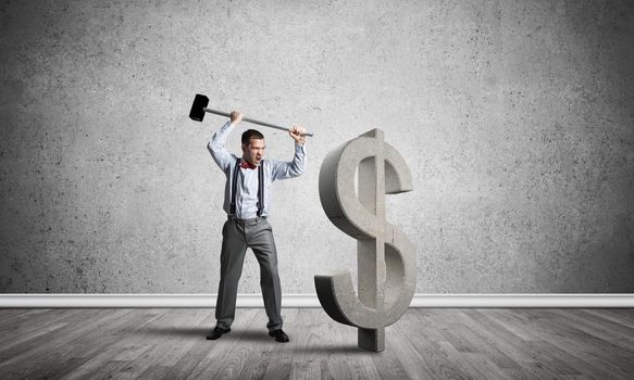 Young furious businessman going to crash with hammer stone dollar symbol