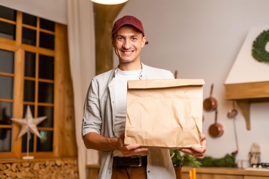 a delivery man with a package of food stands in a Christmas interior