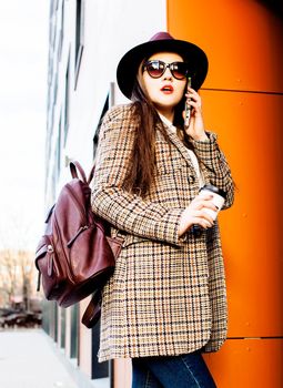 young pretty brunette business woman posing against modern building in hat holding coffee, lifestyle people concept closeup