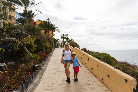 mother and daughter are walking near the ocean on the island of tenerife.