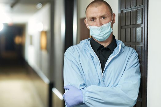 Waist up of man in protective mask standing in hotel corridor. Coronavirus and quarantine concept. Copy space