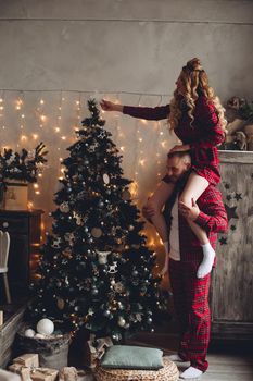 Young woman decorates christmas tree with a man in the living room.