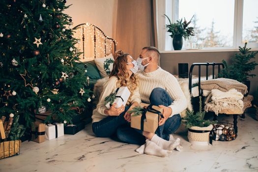 Caucasian girl and her boyfriend in the bedroom in christmas atmosphere with medical masks