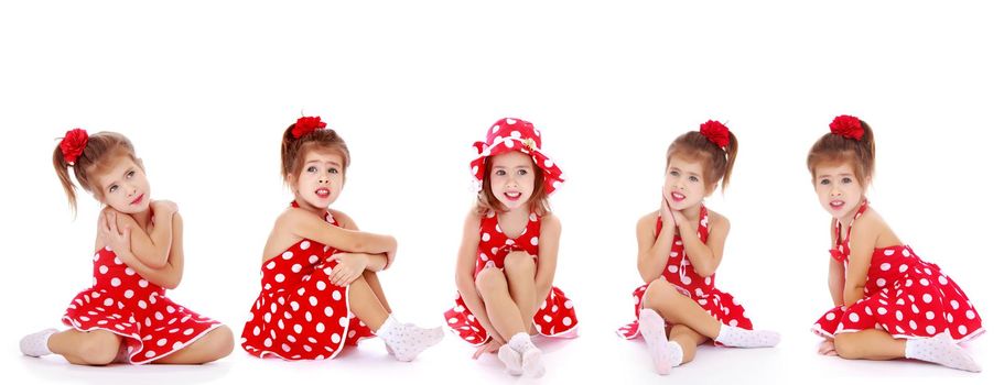 Beautiful little girl is sitting on the floor in the studio. The concept of a happy childhood, beauty and fashion. Isolated on white background.