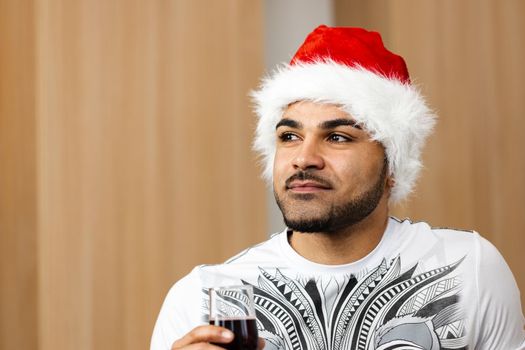 Young african american man in Santa cap drinking red wine, close up portrait