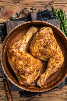 BBQ Grilled chicken legs in a wooden plate with herbs. wooden background. Top view.