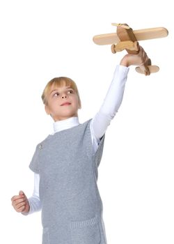Happy little girl is playing with a wooden plane in the studio on a white background. The concept of emotions and children's games. Isolated.