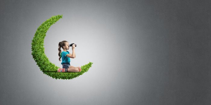 Cute kid girl sitting on green moon and looking in binoculars