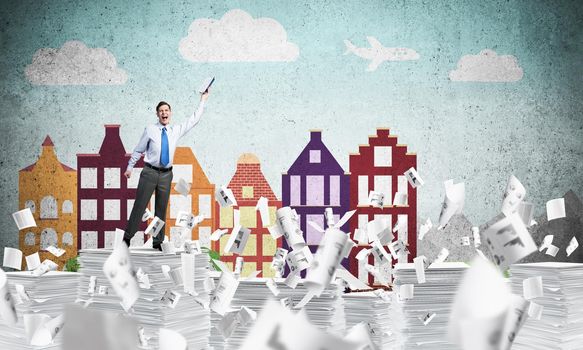 Businessman keeping hand with book up while standing among flying papers with drawn cityscape on background. Mixed media.