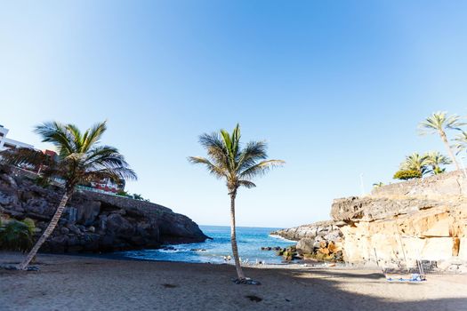Tropical island of Tenerife. The coast of a Spanish city on the Atlantic ocean. Panorama of the city and beach on the island of Tenerife. Background color with gradient and grain, sound effect.