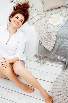 young pretty brunette girl laying in cozy bed with coffee wearing wool winter sweater happy smiling, lifestyle people concept close up