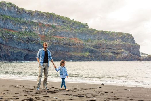 Happy family standing on the beach on the dawn time