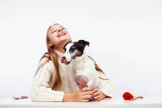 pretty young blond girl with her little cute dog wearing Santas red hat at Christmas holiday isolated on white background, lifestyle people concept close up