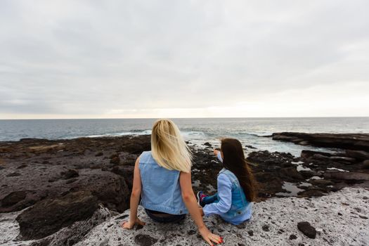 mother and daughter are walking near the ocean on the island of tenerife.
