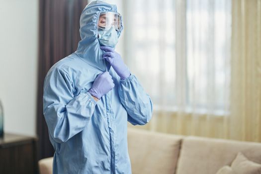 Waist up of worker standing in hotel apartments in protective clothing. Coronavirus and quarantine concept