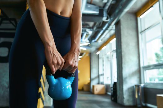 Weight training. Cropped shot of a strong athletic woman exercising with dumbbell at industrial gym, training arms. Sport, workout and healthy lifestyle