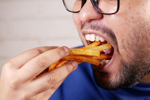 a fat man eating french fries while sited .