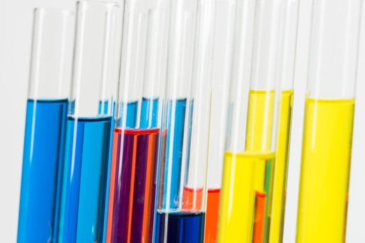 Laboratory analysis and testing. Close up test tubes with colorful reagents on white background. Scientific concept with glass chemical equipment. Pharmaceutical industry research and experiments