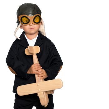 The boy in the helmet of the pilot plays with a toy wooden plane. He dreams of becoming a pilot. Concept of happy childhood, child in the family.Isolated on white background.