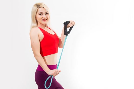 Close up portrait of a confident young fitness woman doing exercises with hand expander isolated over gray background