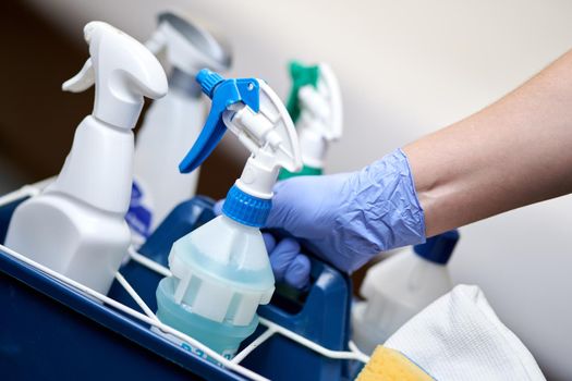 Close up of maid holding basket with cleaning items for room cleaning in hotel. Housekeeping and hygiene concept