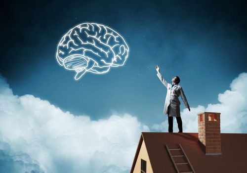 Conceptual image of confident doctor in white uniform interracting with glowing brain symbol while standing on brick roof against night cityscape view on background.
