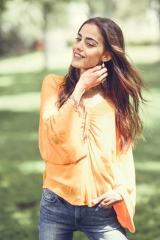 Young woman with nice hair in the wind wearing casual clothes in urban background. Happy girl with wavy hairstyle.