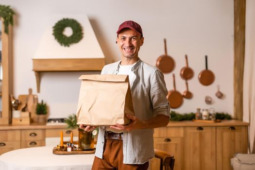 a delivery man with a package of food stands in a Christmas interior
