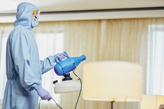 Side view of worker providing a service and making disinfection in hotel room. Coronavirus and quarantine concept