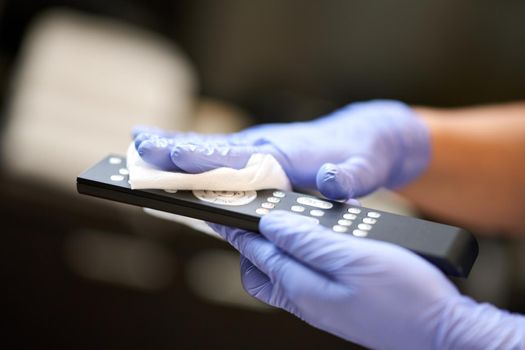 Close up of maid wiping the remote control with a napkin in hotel room. Hotel service concept