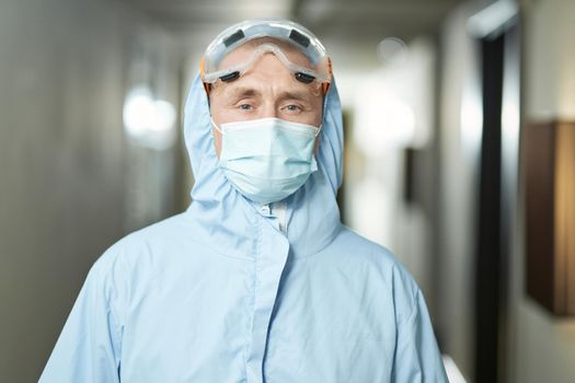 Portrait of man wearing blue suit and mask, glasses before disinfection of the room. Coronavirus and quarantine concept