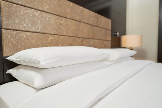 Close up of clean white pillows on a large bed in a hotel suite. Interior design concept