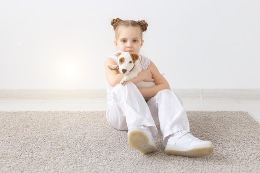 Dogs, pets and animal concept - Little child girl sitting with puppy Jack Russell Terrier.
