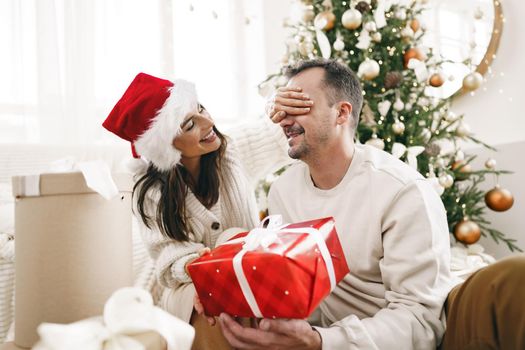 Young cheerful couple in love with present for Christmas, portrait
