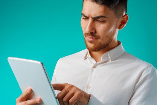 Young businessman wearing white shirt holds digital tablet against green background